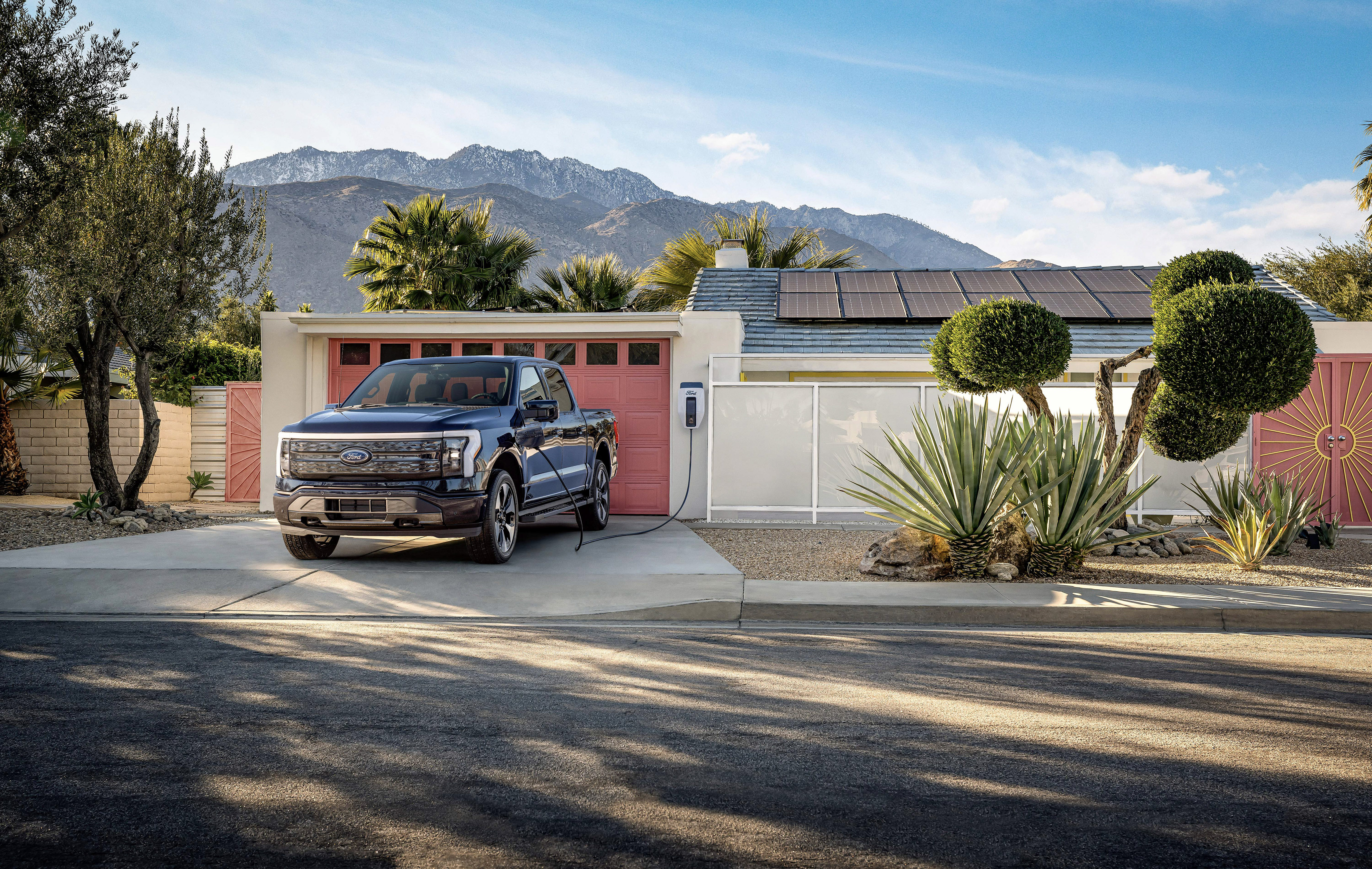 An F-150 Lightning is parked in front of a garage at a home.